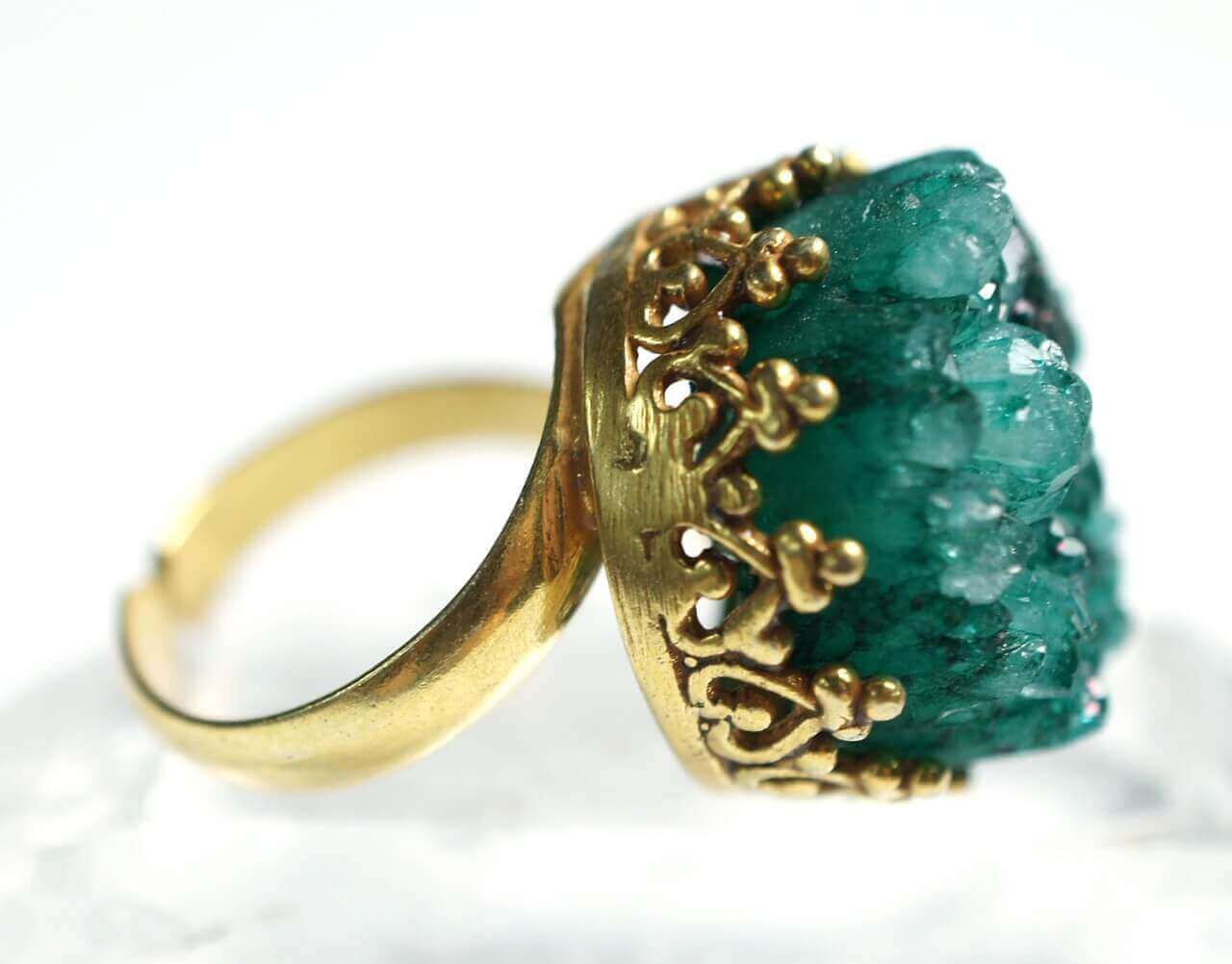 An ornate gold ring with a green quartz center stone