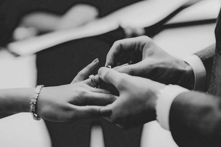 Groom placing wedding ring on a bride’s hand