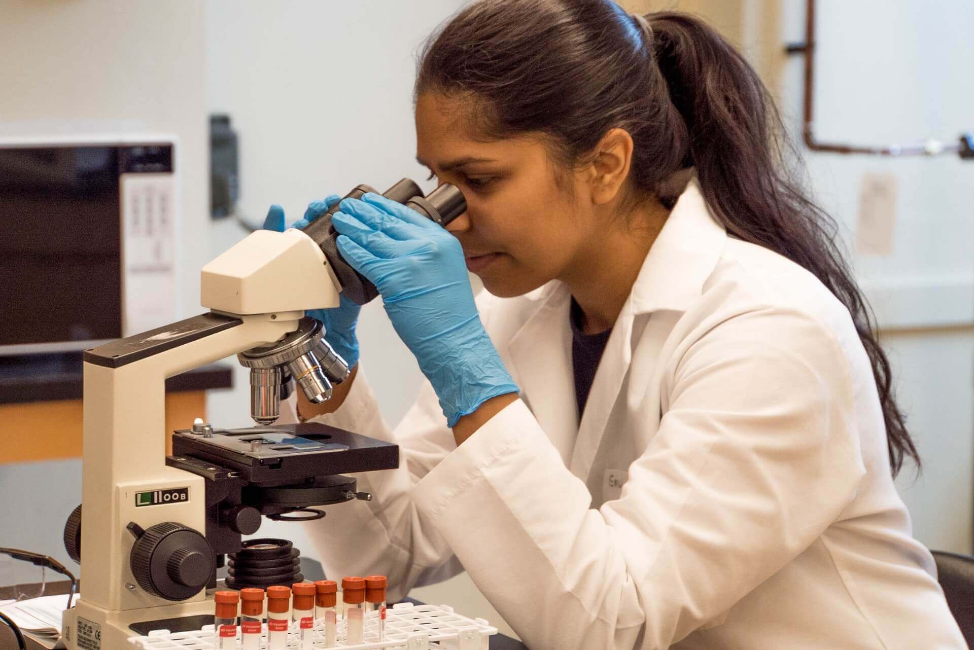 A woman viewing a sample through a microscope