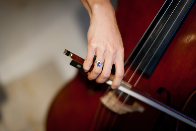 blue topaz halo engagement ring woman playing cello